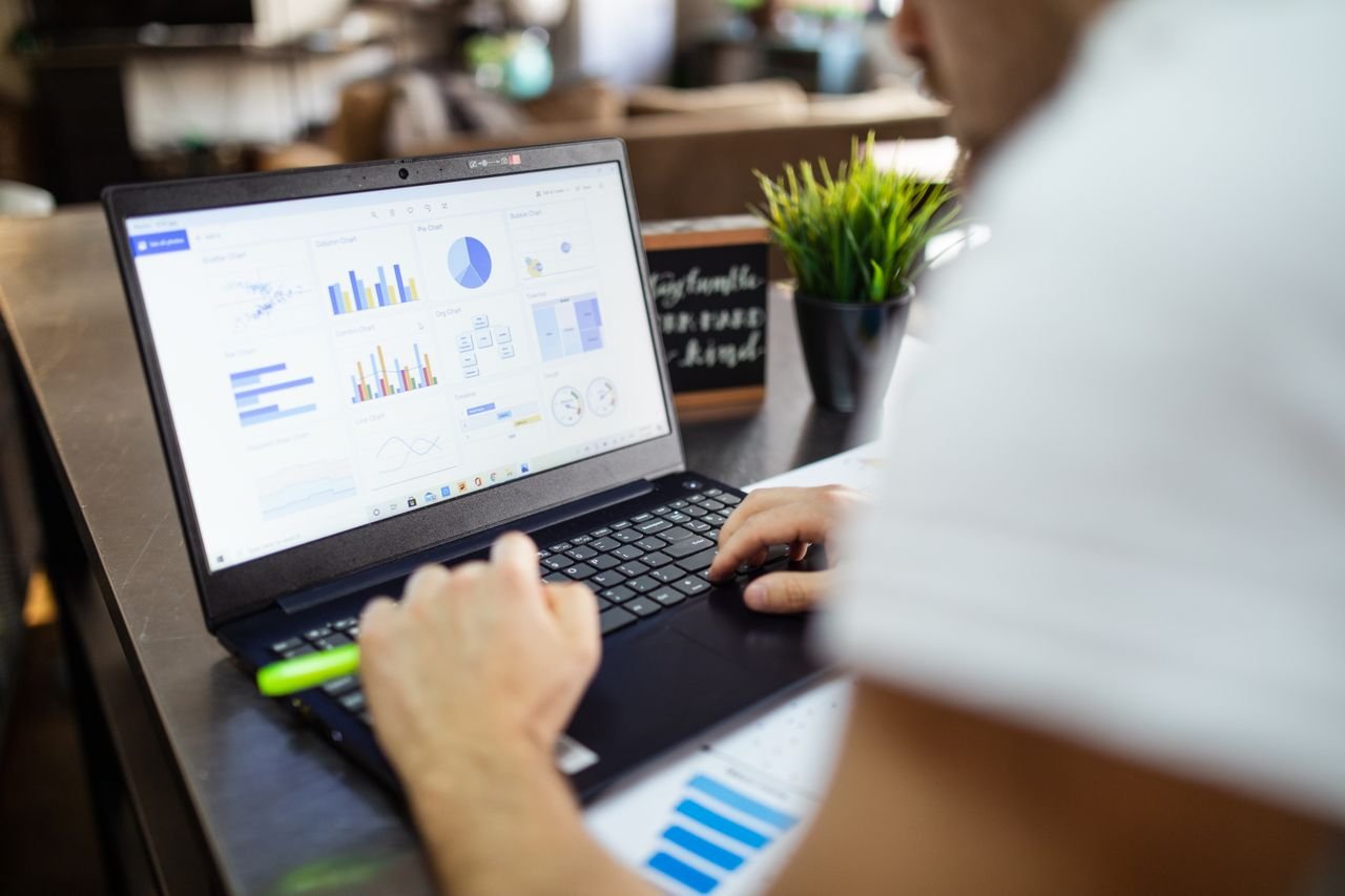 Home Focused business analysis with charts and graphs on a laptop in a modern office setting.